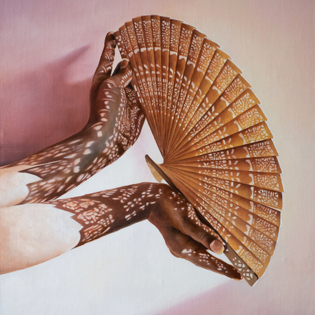 Two hands holding a fan with light streaming through the cut out lace pattern of the fan