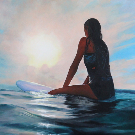 surfer girl sitting on surfboard in the ocean watching the sunrise