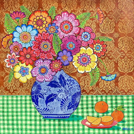 Colourful flowers in blue and white vase in front of red ochre patterned background on green checkered tablecloth with a pink plate of oranges.