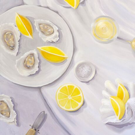 A tabletop view from above showing juicy lemons, oysters, a bowl of salt, and oyster shucker & a seashell.