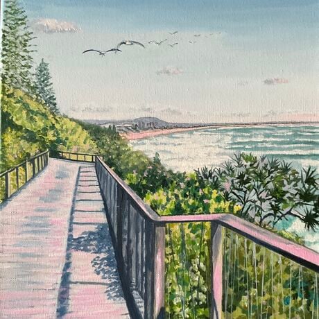 Beach boardwalk along the coast, framed by pandanus and coastal shrubs, seagulls overhead and views in distance,