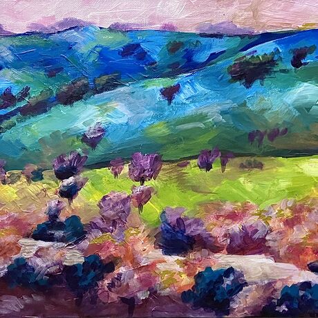 A multicoloured view of hills, trees and a river, in blues, greens, yellows, pinks and purples.