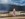 Barefoot girl in strawberry dress on paddock fence line with looming storm in the background