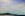 Coastal scene with headland in the distance, large sky overhead and beach and ocean below.