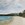 White and grey clouds forming over Kunanyi Mt Wellington with many shades of blue sky poking through. Smaller hills in the distance and Bellerive Beach sand and water.