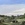 A farming landscape depicting natures old trees and boulders and a shearing shed and fence. 