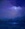 A purple hazy background with soft clouds in the top quadrant.  A glimpse of the moon through the clouds that are varying blend of purple into yellow gold sitting behind an out of focus tree line.  The foreground shows a body of water with gentle waves in dark blue