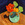 Yellow and orange flowers in a green Arts and Crafts vase on a deep blue background.