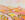 An imaginary landscape with a variety of hills, mountains and fields with different trees lining fields under a soft pink sky - everything is kept in pink and yellow tones. 