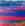 A seascape scene of stunning red sands and blue sea depicting New Caledonia , with rolling tropical mountains in the background.