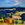 This is a landscape of rolling hills in pastureland with blue mountains in the background and both paddocks and Scrubland in exaggerated blues and autumnal colours