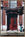 a woman walks past a set of old red doors in France