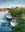 The image is of 3 fishing boats moored after being out fishing on the ocean. The boats at moored at a creek where the ocean flows into the creek at high and low tide. The  creek is has a grove of mangroves on the right side creating a lush green backdrop.  