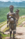 A Karo woman stands on a rocky outcrop holding a baby. The plains and mountains are in the background.