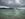 Catamarans on jade waters sailing while a storm approaches . 