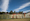 A line of green corrugated iron fences at the back of a row of houses. 