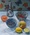 Bowls of berries, an apple, lemons, mandarin and silver oil jug on white tablecloth 
