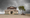 A cream and red majestic building sits on a sandy beach at low tide with a mangrove tree under an approaching storm. An eagles nest is perched on top of the building and being circled by its resident. 