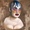 A portrait of a bust of Leigh Bowery, who sports a painted face with huge red lips, orange cheeks and highlights and pink eye shadows. Blue candle wax drips down the figures bald head creating the illusion of bizarre looking hair.