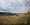 little old house on a prairie field with mountains in the distance.