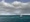 White Cabin houseboat floating on turquoise water with cloudy skies overhead.