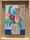 Beautiful smooth natural wood frame surrounding a small canvas board painted with brightly coloured abstract flowers in a small ceramic vase.