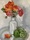 A bunch of poppies in a white ceramic vase sits in a bowl with Limes
