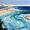 Seascape of a beach with tiny figures on the sand and in the water swimming.