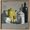 four vintage objects sit on a mid grey surface. A small white bowl, a yellow enamel coffee pot, a lidded white enamel canister and a taller olive green bottle. the background is a light grey