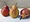 Three luscious red blushed pears on a table, 2 standing, 3rd laying down