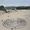 A painting of a huge maze made of sand on Currumbin Beach with coloured balls trying to enter it