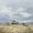 an old house in a dry grassy field with bare trees and blue sky