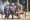 Three elderly men sit and talk on a street bench 