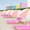 Foreground contains a row of magenta sunlounges accompanied by pastel pink and white sun umbrellas, lined up along the sand on Miami's famous South Beach, out front of the SLS South Beach hotel. The background features the treeline where the beach meets the street, and a row of pastel coloured high rise buildings span the length of the street behind the treeline.