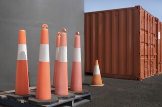 Orange bollards standing in a group in front of a storage container in an urban landscape setting 