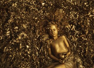 Golden statue of a girl - king midas’ daughter- curled up on a bed of golden foliage. 