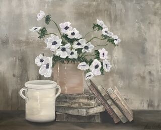 On a table top there is a stack of old books that have a rust coloured pottery vase of beautiful white flowers  sitting  on top , there is another stack of books leaning upward to one side and another rustic on the opposite end that is empty..
