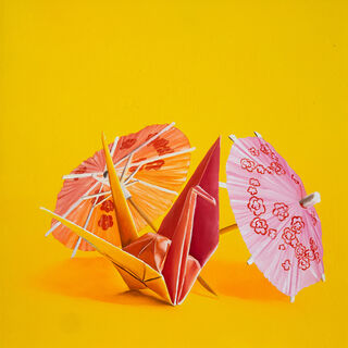 An origami bunny standing amongst cocktail parasols against a yellow background