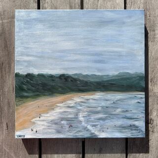 A view of Pambula Main Beach with people swimming in the water and a backdrop of the green hills in the background. 