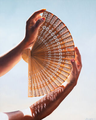 Hand holding an intricate fan with light streaming through the fan, casting a pattern of shadows across the hand.