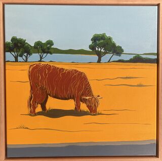 Shaggy brown cow on yellow field with green trees and blue sea in the background.