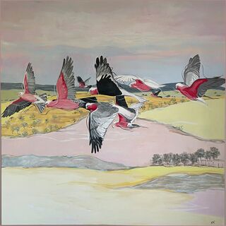 A flock of galahs flying across the landscape