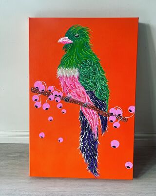 one neon coloured bird with dot patterned bright feathers sitting on a branch surrounded by gum nuts with a bright orange back ground.