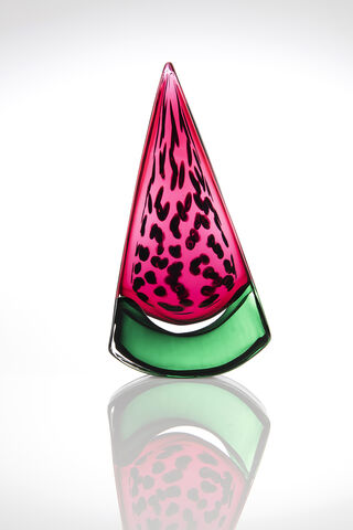 Solid glass watermelon slice with pink top half, green base and internal scattered black seeds