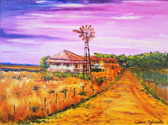 Australian outback house with red roof. Dry yellow grass all around it. A windmill next to it. Pink sky. Hills in the background. 