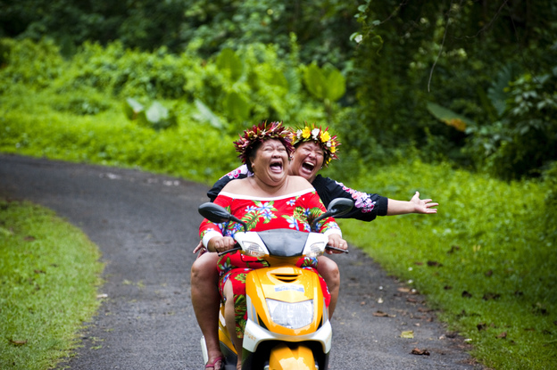 Two happy women ride a motorbike in the Cook Islands