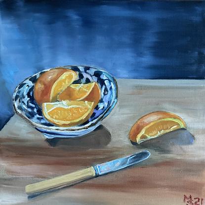 A cut orange sitting in a Japanese bowl with knife