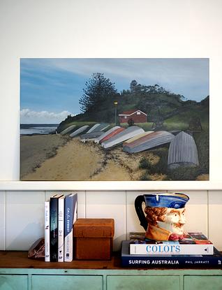 A row of dinghies resting on the foreshore of Long Reef Basin at Fishermans Beach. 
The ocean in the back ground and a bush covered headland framing the fisherman's hut. 