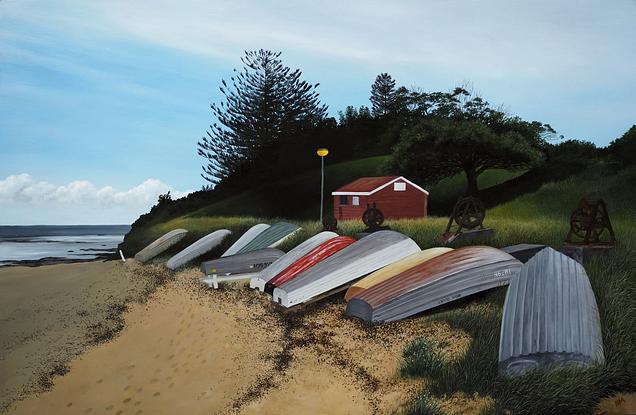 A row of dinghies resting on the foreshore of Long Reef Basin at Fishermans Beach. 
The ocean in the back ground and a bush covered headland framing the fisherman's hut. 