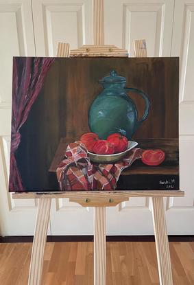 Still life painting of a green jug and a bowl of ripe tomatoes sitting on a tea towel, placed on an old wooden table. The painting tries to capture a rustic background with a knotted drapes hanging by the side.